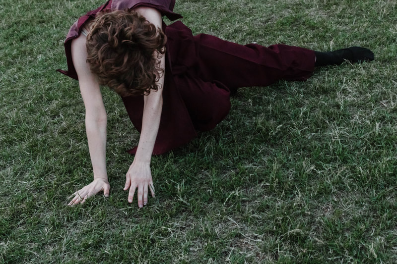 a photograph of a dancer rolling across the grass, by Minnesota based fine art dance photographer Kayla Schiltgen