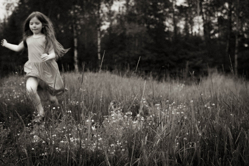 a black and white photograph of a young girl running through  a meadow, by Two Harbors photographer Kayla Schiltgen