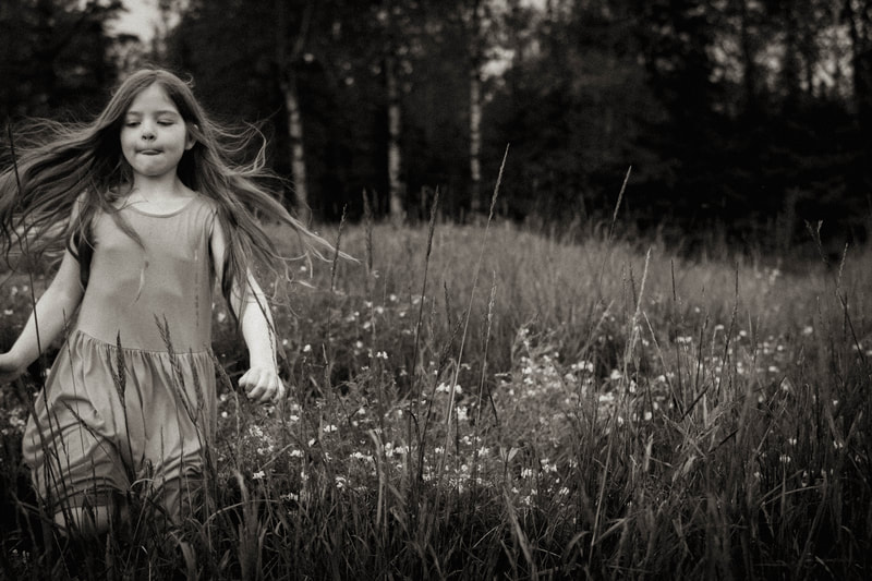 a black and white fine art photograph of a little girl running through a meadow, by Two Harbors, Minnesota based family photographer Kayla Schiltgen