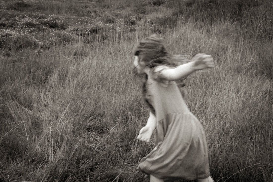 a black and white photograph of a little girl twirling in a meadow. By Minnesota based, fine art, family photographer Kayla Schiltgen