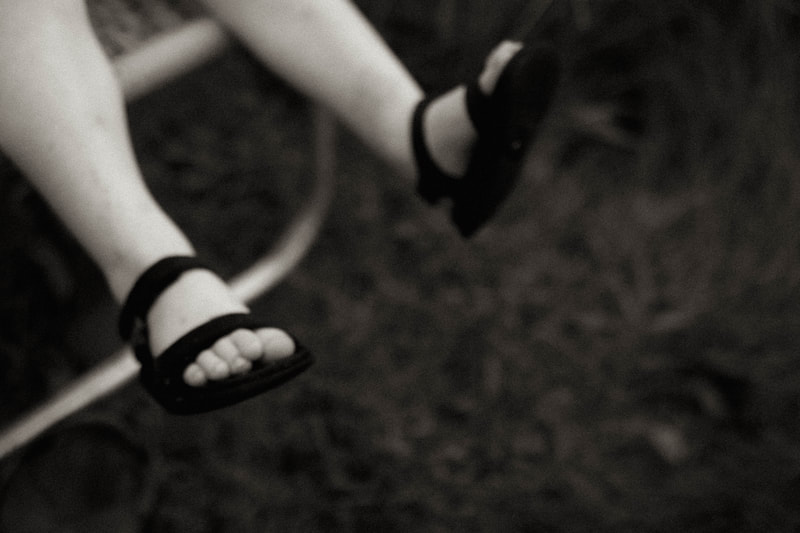 black and white fine art photography of a little boys feet as he sits in a lawn chair, by Two Harbors based family photographer Kayla Schiltgen